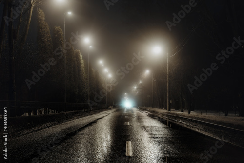 Foggy misty night road illuminated by street lights