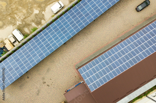 Aerial view of solar power plant with blue photovoltaic panels mounted of industrial building roof.