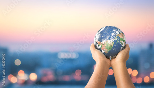 Earth Day concept:  Human hands holding earth global over blurred city night background. Elements of this image furnished by NASA