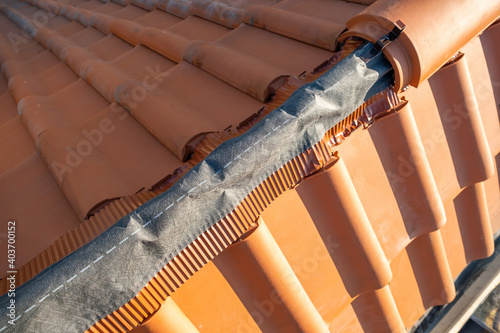 Fototapeta Closeup of yellow ceramic roofing ridge tiles on top of residential building roof under construction