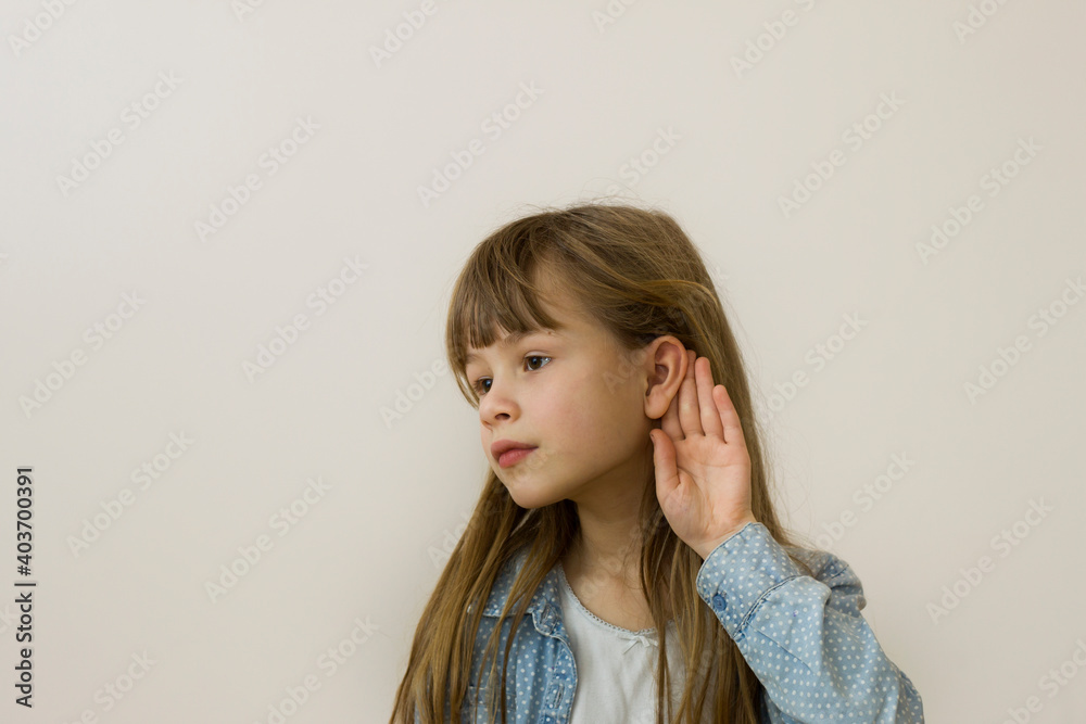Young pretty child girl with long loose hair, dreamy eyes and serious face expression listening on light background. Young pretty child girl with long loose hair, dreamy eyes and serious face expression listening on light background.