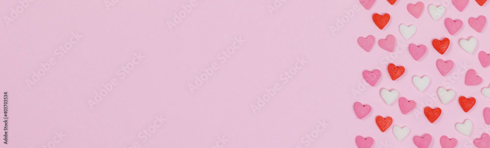 Heart shaped candies scattered on pink background