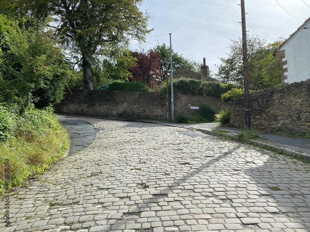 View near the bottom of, Thwaites Brow Road, with stone cobbles, and residential housing in, Thwaites, Keighley, UK