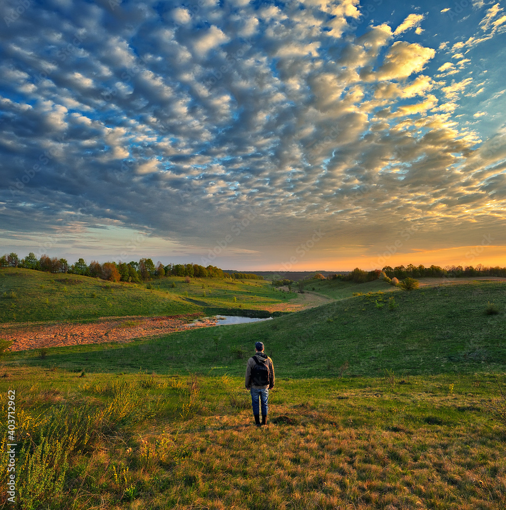 man on the banks of the picturesque river. tourist is enjoying the morning landscape. colorful spring sunrise