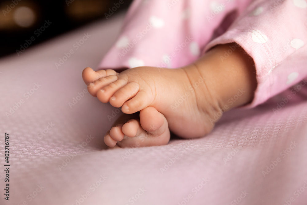 Newborn baby girl legs on lilac background, infant barefoot at natural light Newborn baby girl legs on lilac background, infant barefoot at natural light