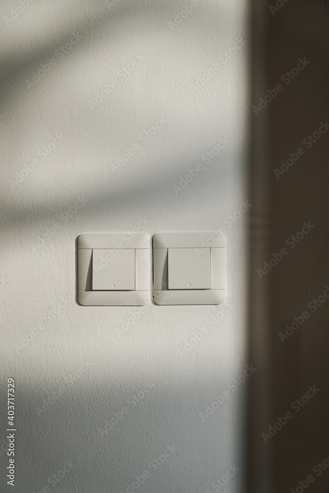 Two switches on the wall in the late afternoon sun.