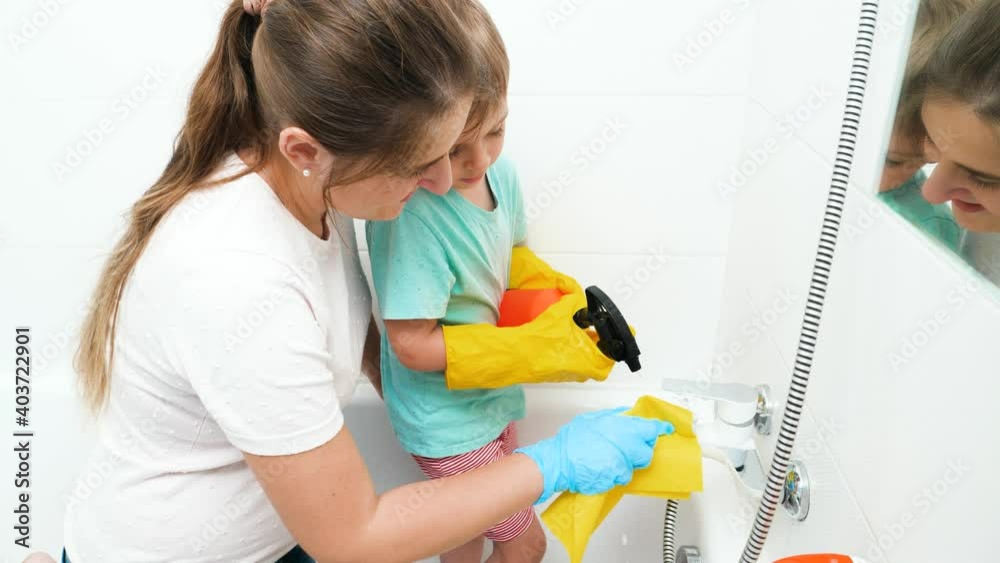 Little toddler boy with mother washing and cleaning water tap in bathroom. Happy smiling family doing house cleanup and housework Little toddler boy with mother washing and cleaning water tap in bathroom. Happy smiling family doing house cleanup and housework