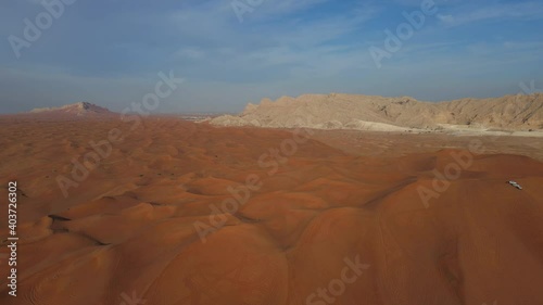 UAE Desert:  Top View of Sharjah Desert, A group of 4x4 vehicles, rides on Giant Sand Dunes, Mleiha Mountains in the Background. 4k Footage photo