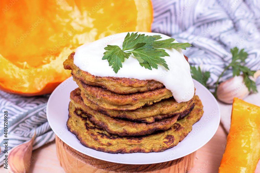 Traditional homemade vegetarian pumpkin potato pancakes with sour cream on light background. Traditional homemade vegetarian pumpkin potato pancakes with sour cream on light background.
