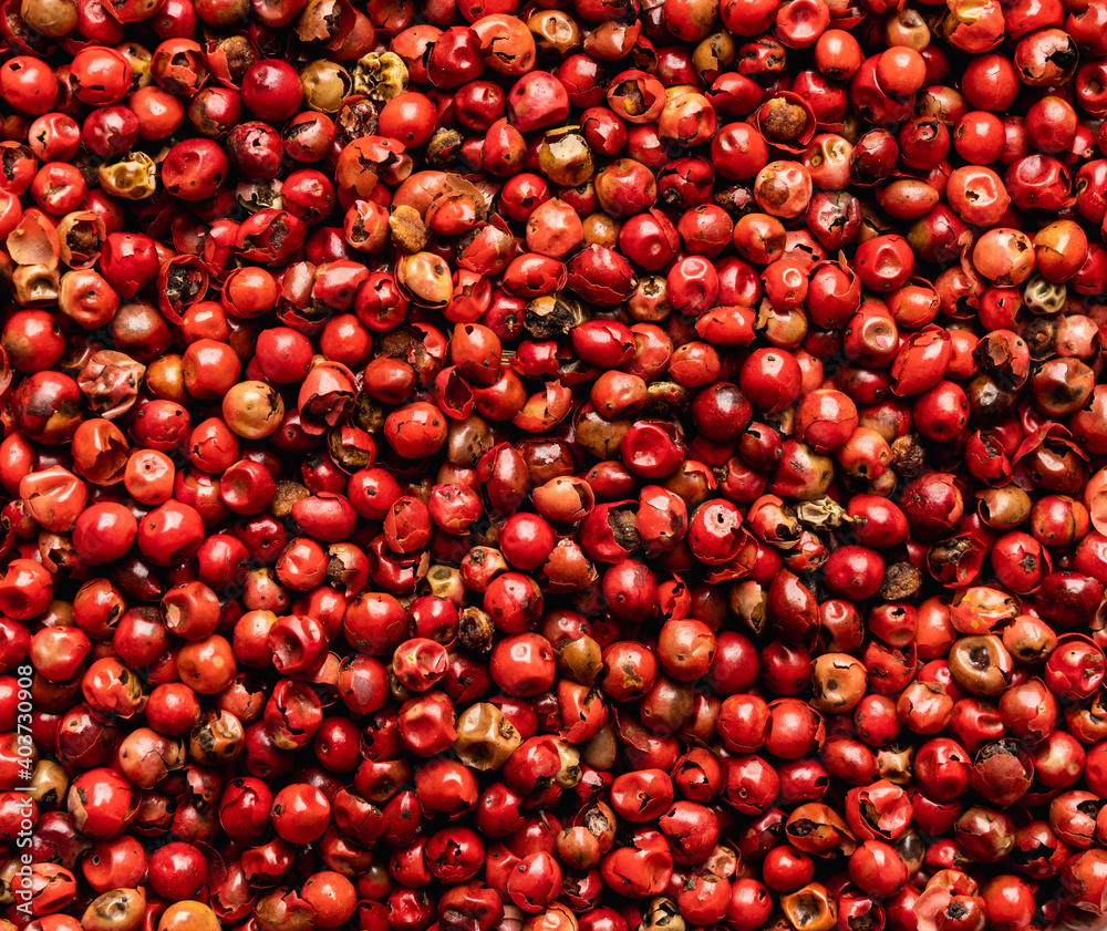 Red peppercorn on the black stone background. Shot from above. Background and textures. Red peppercorn on the black stone background. Shot from above. Background and textures.