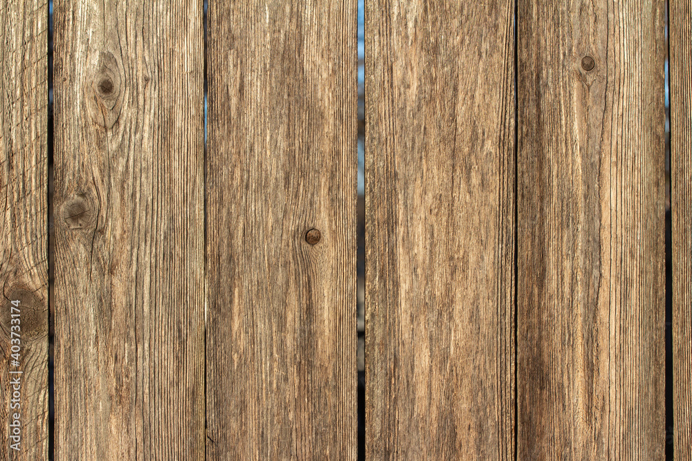 Full frame texture background of a wooden fence with natural wood grain planks, in bright sunlight Full frame texture background of a wooden fence with natural wood grain planks, in bright sunlight