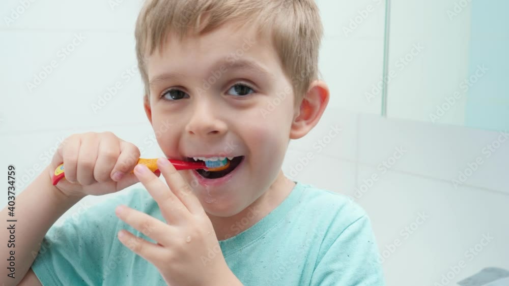 Funny toddler boy smiling and laughing while brushing and clening teeth with toothbrush in bathroom Funny toddler boy smiling and laughing while brushing and clening teeth with toothbrush in bathroom