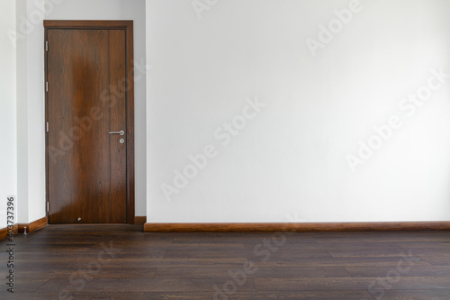 The empty room has wooden floors and wooden doors.