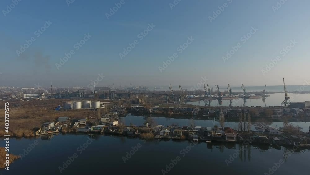 Aerial view. Cranes, warehouses, buildings and factory chimneys are outlined against foggy background of summer river Aerial view. Cranes, warehouses, buildings and factory chimneys are outlined against foggy background of summer river