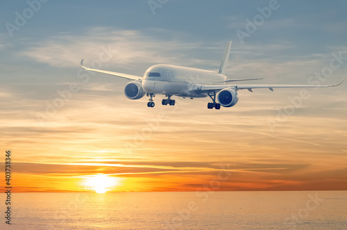 Plane at sky over sea at sunset