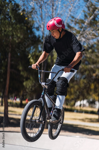 Latino young man practicing jumping on a bicycle. concept activities in urban park