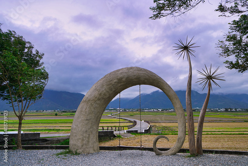 Tree-shaped installation art and swings, in front of curved asphalt roads. Hualien County, Taiwan is a very popular place for leisure travel.