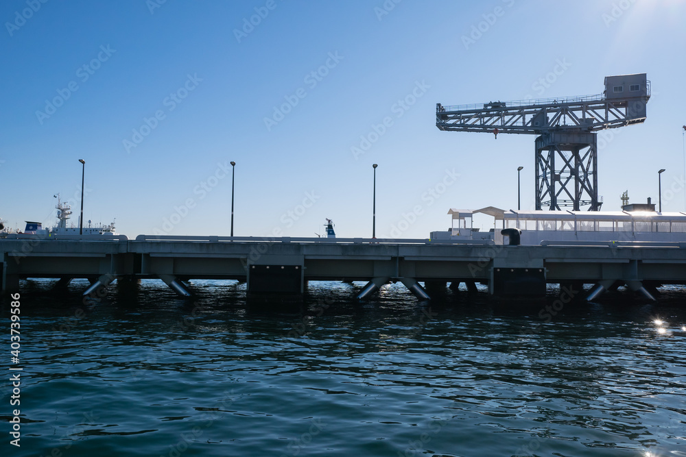 Obraz premium 日本の横浜にある客船ターミナル。クルーズ船が停泊する桟橋とシンボルのハンマーヘッドクレーン。