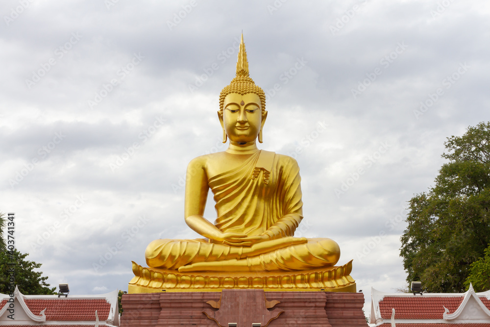 Beautiful Big Golden Buddha statue against blue sky in Thailand temple,khueang nai District, Ubon Ratchathani province, Thailand.Amazing Buddha image with sunny sky clouds.