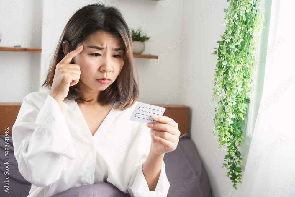 Asian woman forget to take birth control pill sitting in bed with worry face Asian woman forget to take birth control pill sitting in bed with worry face