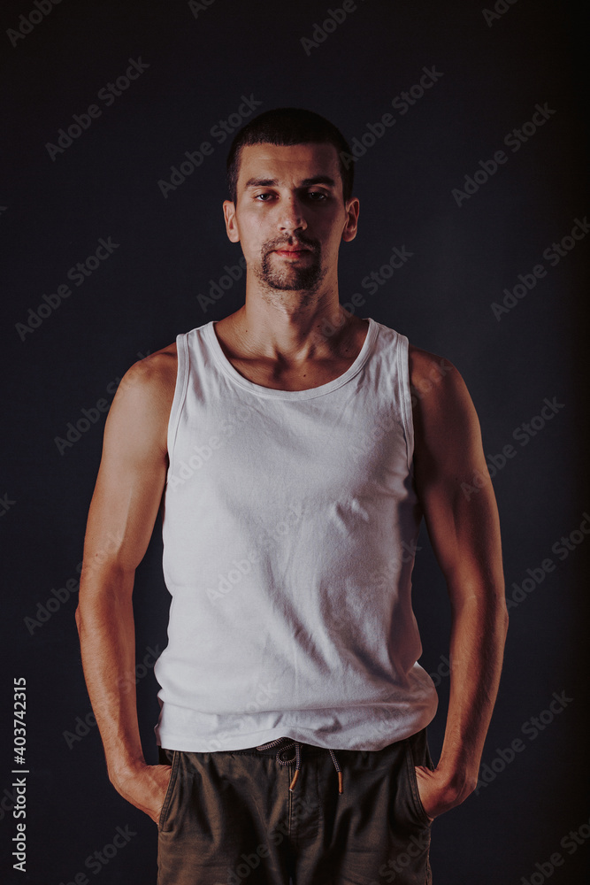 handsome tanned athletic man in a white t-shirt on a wall photo handsome tanned athletic man in a white t-shirt on a wall photo