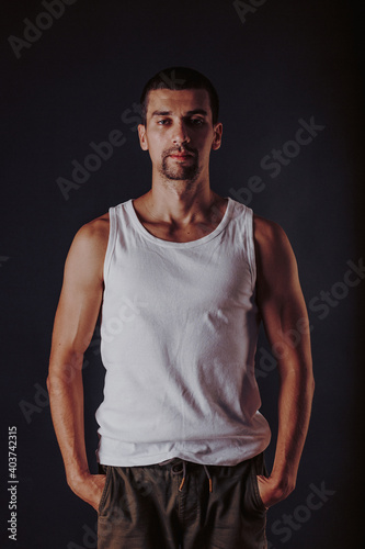 handsome tanned athletic man in a white t-shirt on a wall photo