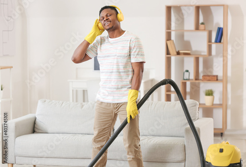 African-American man listening to music while hoovering his flat photo