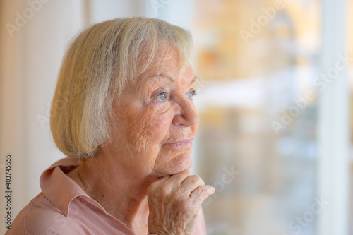 Thoughtful elderly lady with hand to chin