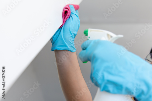 Employee's hands were wiping the white walls, use a towel moistened with cleaning solution to rub the wall, Text fill area, White background, Eliminate germs during the virus outbreak.