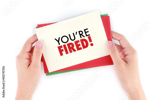 Hand holding card and envelope with message "You're Fired"