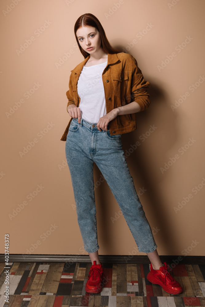 Girl in jeans and a brown jacket posing on a beige background Stock ...