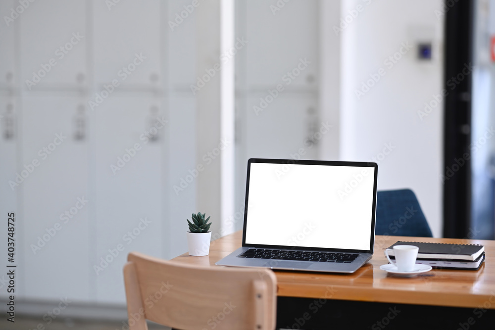 Mock up laptop computer with white screen on wooden table in modern office. Mock up laptop computer with white screen on wooden table in modern office.
