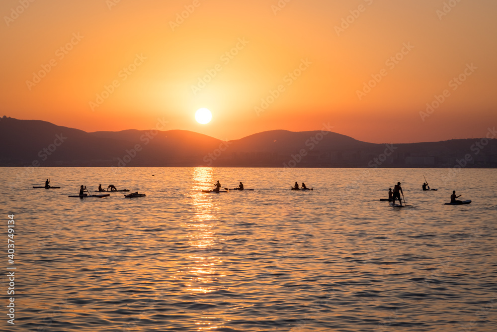 Stand up paddle boarders SUP silhouettes on the water of the sea. Sunset landscape Stand up paddle boarders SUP silhouettes on the water of the sea. Sunset landscape
