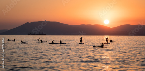 Stand up paddle boarders SUP silhouettes on the water of the sea. Evening, sunset at sea. Active rest on the sea