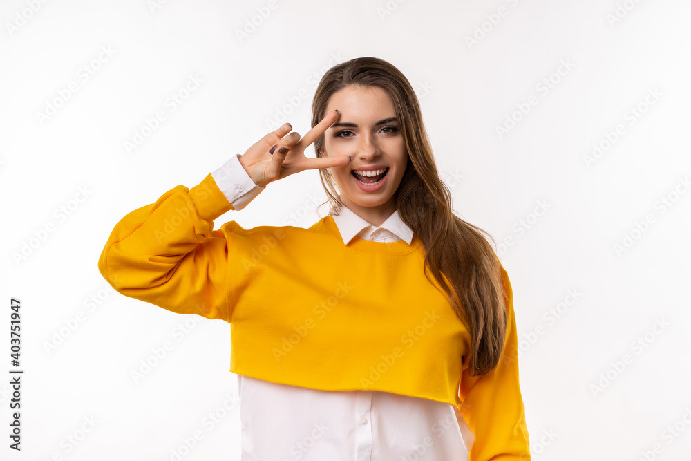 Portrait of optimistic brunette girl showing peace sign over eye and smiling Portrait of optimistic brunette girl showing peace sign over eye and smiling