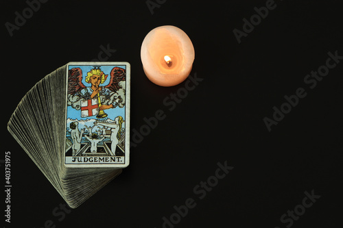 The Judgement Tarot cards With a white candle lit With a black space on the left to write a message.