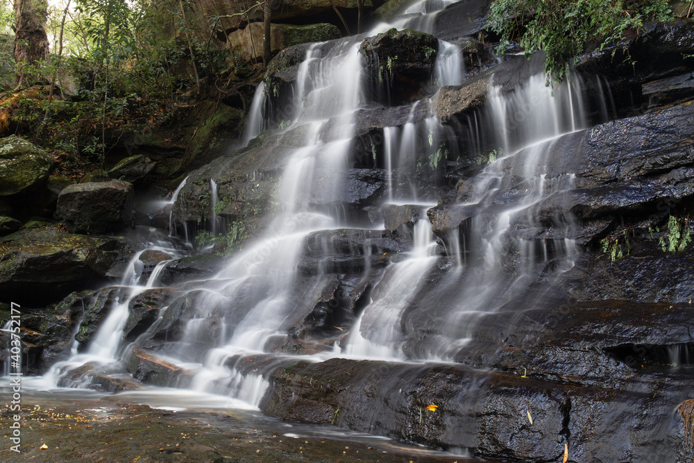 Fototapeta premium Side view of a tall rocky waterfall.