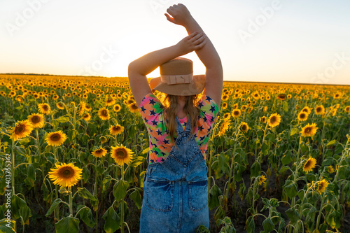 Ukraine. Summer evening. Girl with a hat in a field with sunflowers.