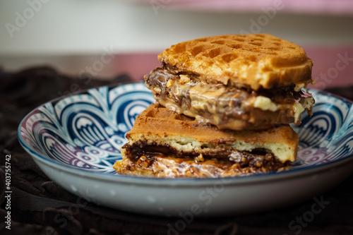 Fresh waffles with peanut butter and chocolate spread on a decorated plate.