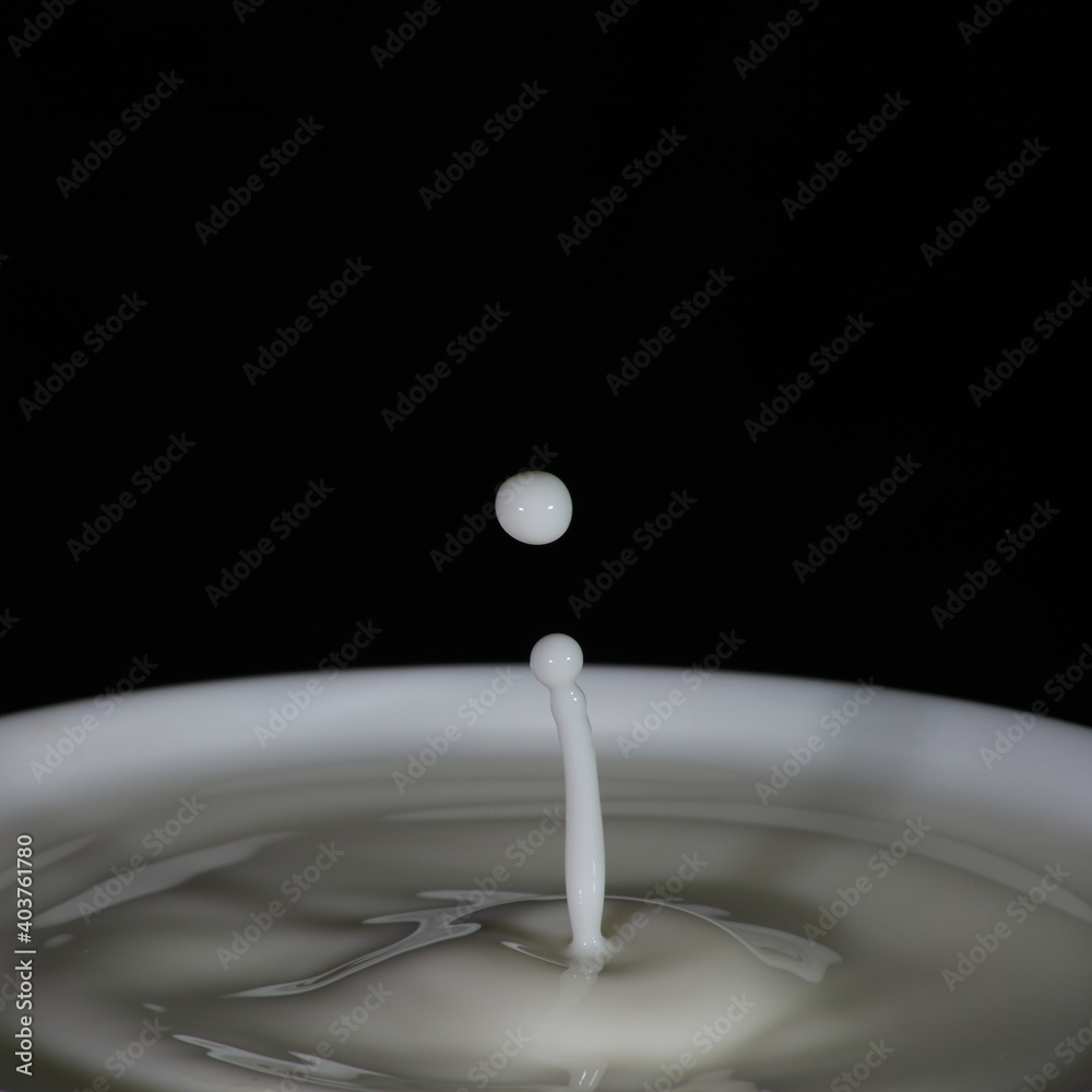 Gotas de leche cayendo a una taza llena Gotas de leche cayendo a una taza llena