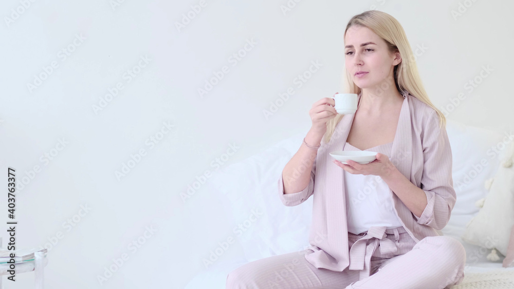 beautiful young woman with cup of coffee in a romantic setting. Front view woman with coffee cup looking at camera sitting on a couch. selective focus. beautiful young woman with cup of coffee in a romantic setting. Front view woman with coffee cup looking at camera sitting on a couch. selective focus.