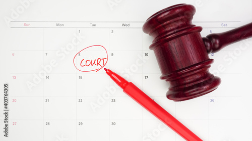 The words Court written and judge's gavel on the white calendar to remind you of an important trial date. Top view.