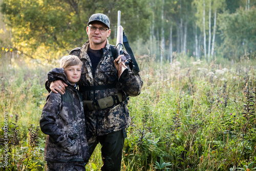 Father and son walking together outdoors with rifle for hunting
