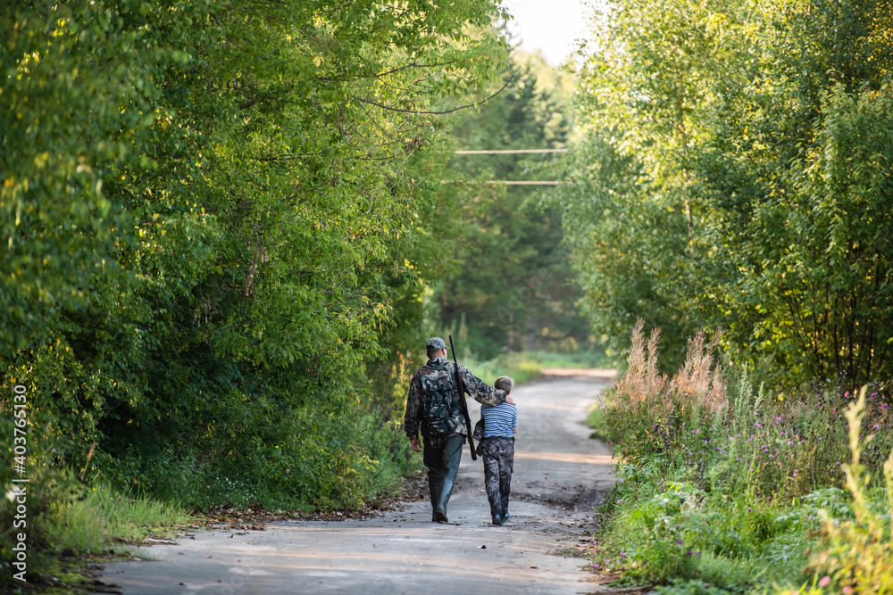 Father and son walking together outdoors with shotgun hunting gear. Father and son walking together outdoors with shotgun hunting gear.