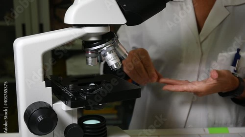 Biology lesson. Teacher is using an optical microscope to carry out her lesson.