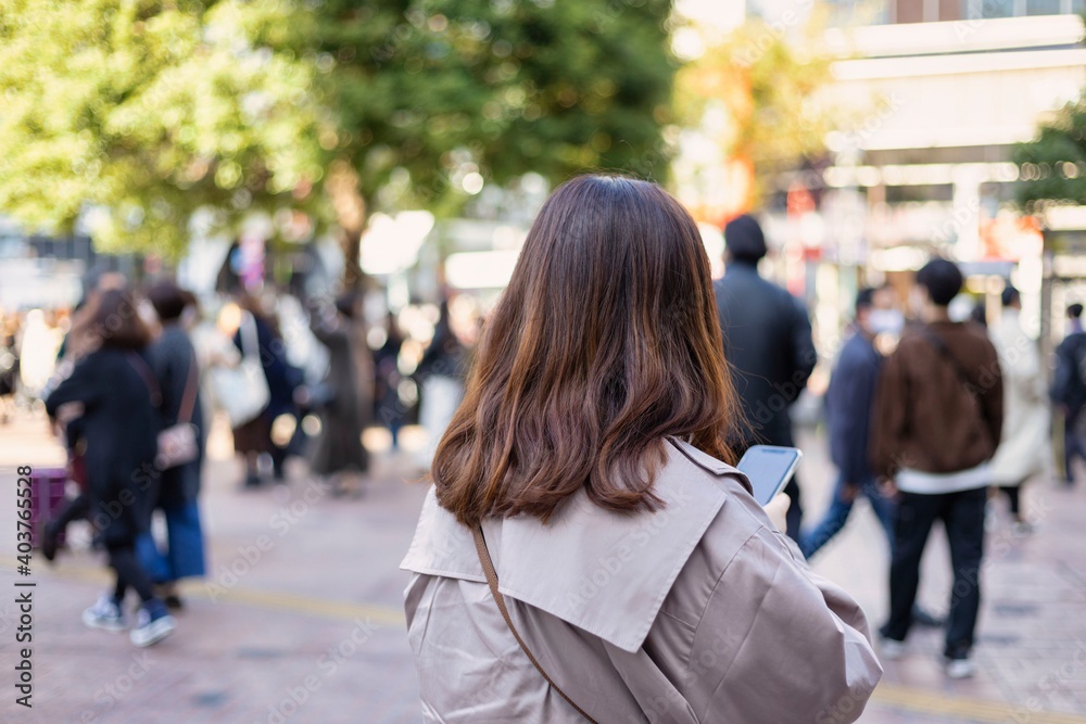 渋谷駅前でスマートフォンを見る若い女性 渋谷駅前でスマートフォンを見る若い女性