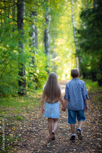 Beautiful boy and girl walking in the beautiful summer forest