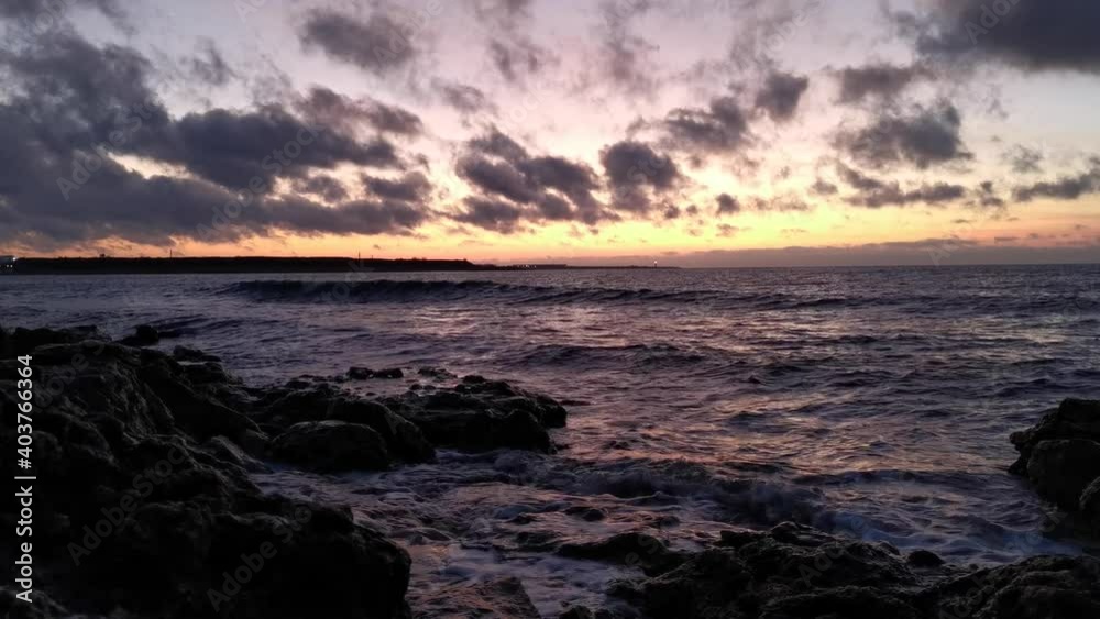 Big waves crash against the rocks. Storm at sea at sunset. The low line of the horizon, a close-up of the rolling waves. Slow motion of flying spray. Natural sea background in the warm sunset light. Big waves crash against the rocks. Storm at sea at sunset. The low line of the horizon, a close-up of the rolling waves. Slow motion of flying spray. Natural sea background in the warm sunset light.