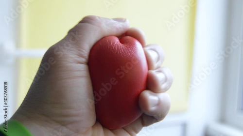 Patient (human) squeezes in his hand (palm) heart shape - carpal expander close up. Video for visualization of the heart beats, sports, development of muscles or hand movements after stroke or injury photo