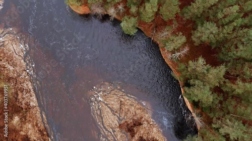 Red sandstone cliffs in the banks of river Salaca during late autumn time, Latvia. Real time drone footage photo